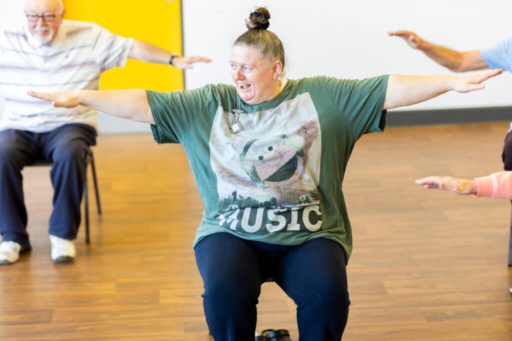Adults take part in a seated group exercise class