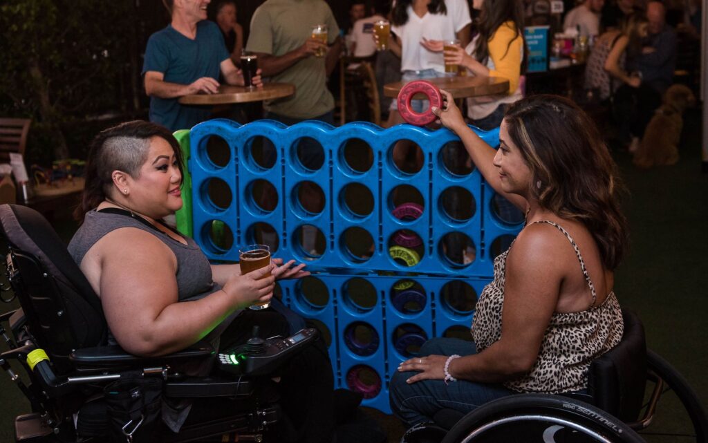 Friends who use wheelchairs play a giant game of Connect Four