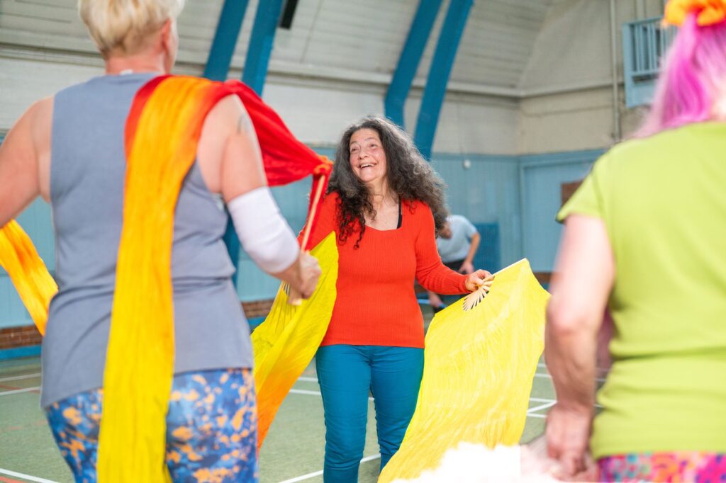 Women move with bright scarves in a joyful group movement class