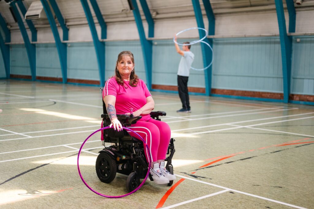 A woman in a wheelchair takes part in a hula-hoop fitness class
