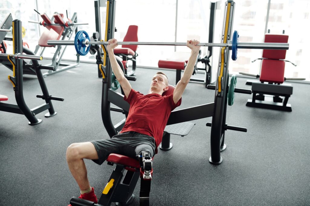 A young man with a prosthetic leg lifts weights at the gym