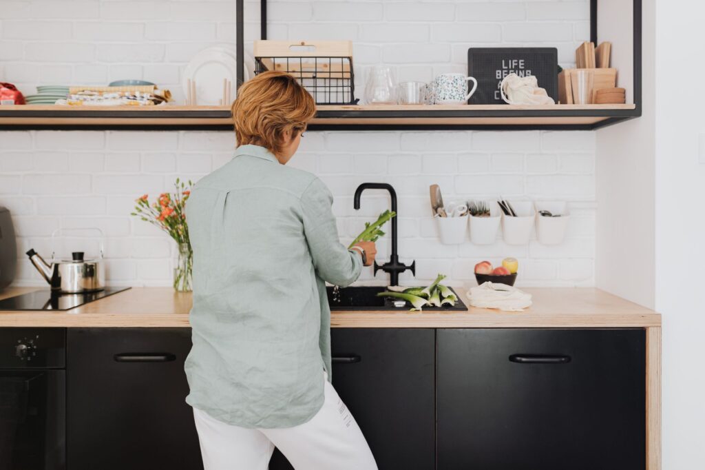 A woman prepares fresh vegetables at her kitchen counter