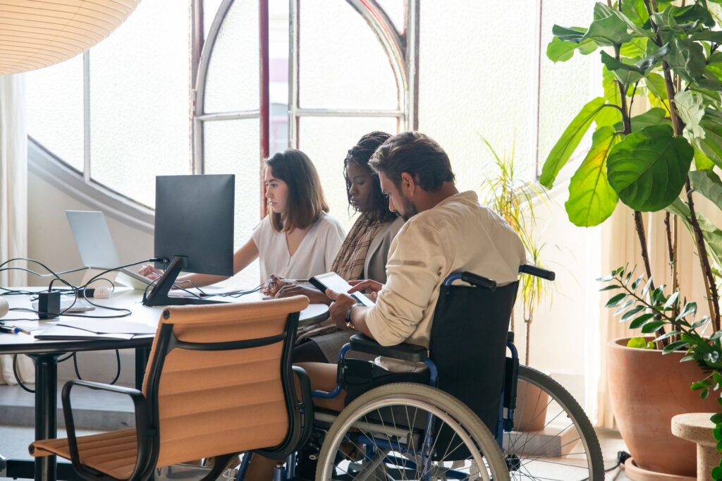 A team that includes a colleague in a wheelchair works together in an office