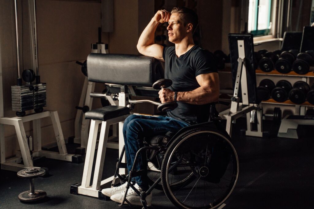 A man in a wheelchair lifts dumbbells during a strength session
