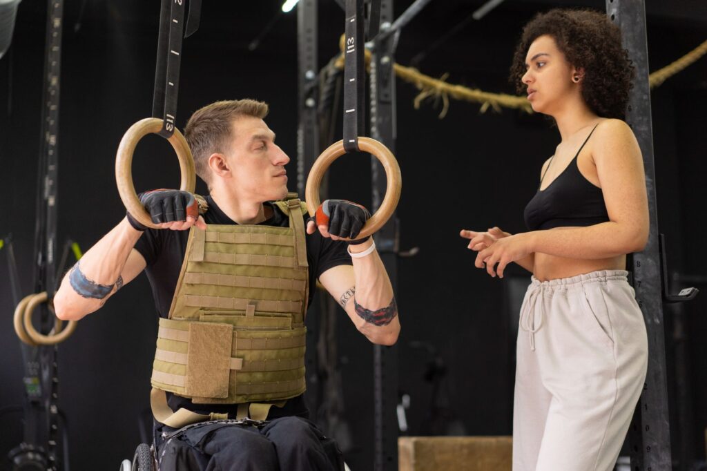An adaptive athlete trains on gymnastics rings with a coach
