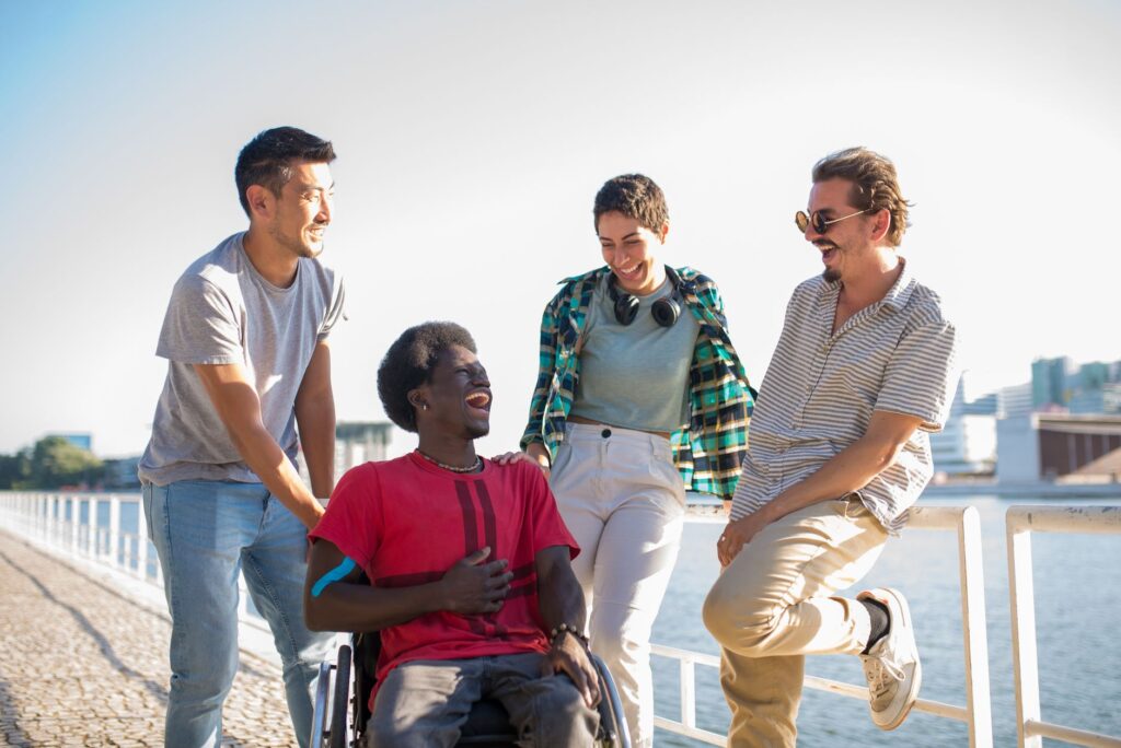 Friends, one in a wheelchair, enjoy an afternoon by the water